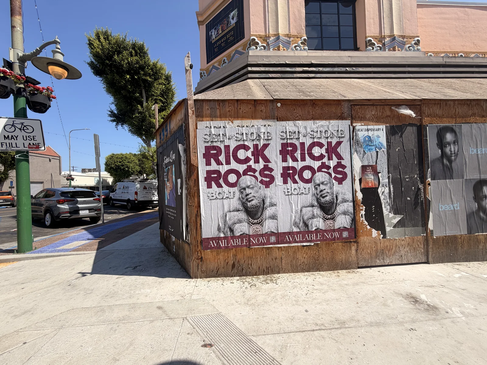 Two Rick Ross Set In Stone posters on a wood-clad street corner