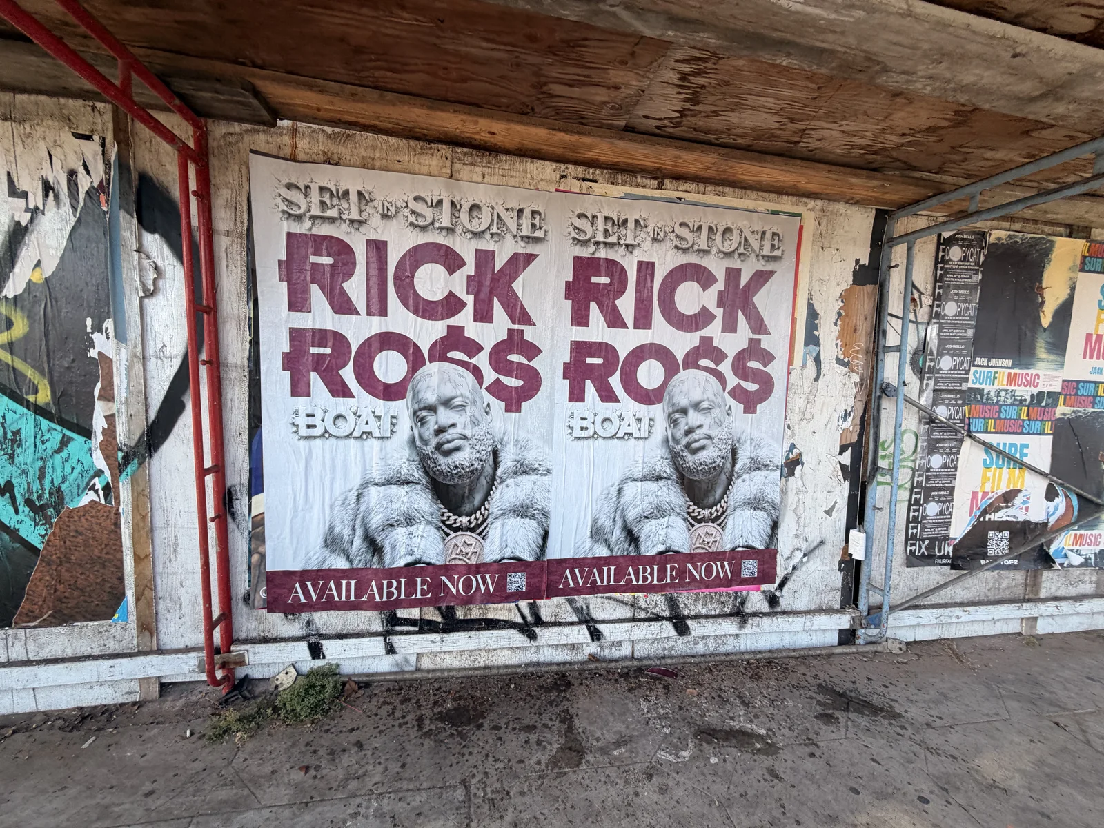 Two Rick Ross Set In Stone posters displayed beneath scaffolding